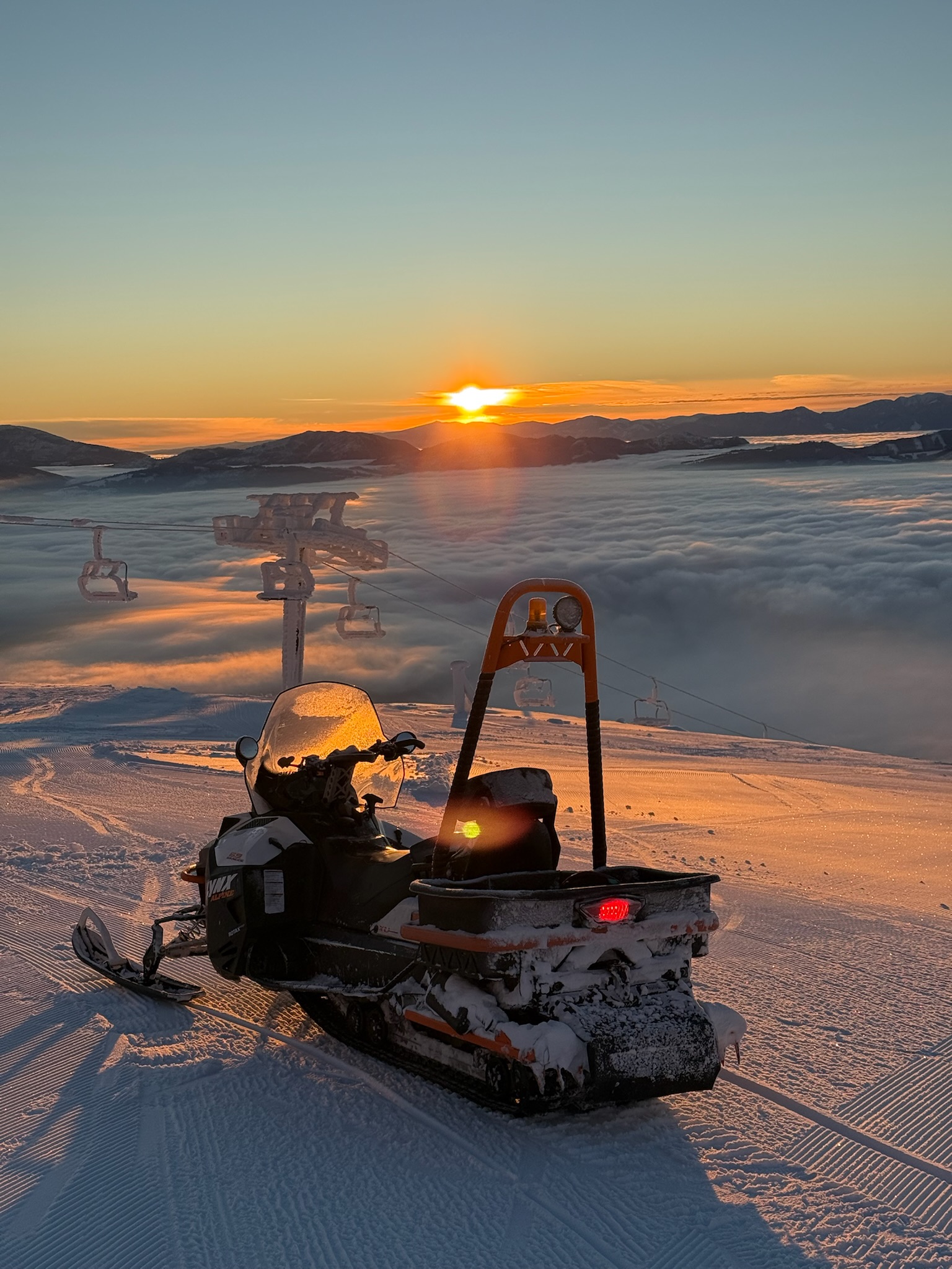 Ski equipment by a chairlift as the sun rises above the clouds